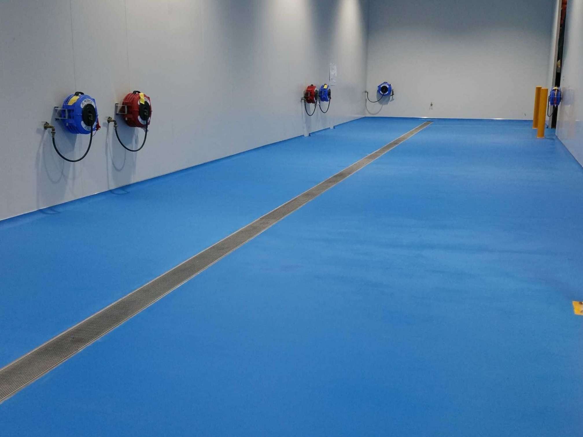 Blue epoxy flooring in food factory with trench drain in Sydney